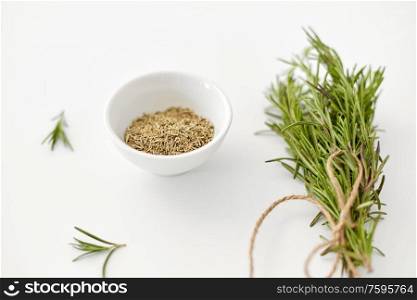 greens, culinary and flavoring concept - bunch of fresh rosemary herb and dry seasoning in cup on white background. fresh and dry rosemary on white background
