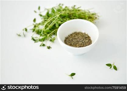 greens, culinary and flavoring concept - bunch of fresh thyme herb and dry seasoning in cup on white background. fresh thyme and dry seasoning on white background