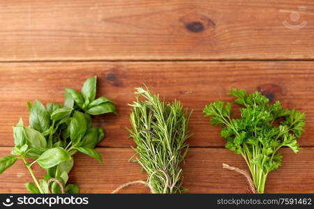 greens, spices or medicinal herbs concept - bunches of parsley, basil and rosemary on wooden boards. greens, spices or medicinal herbs on wooden boards