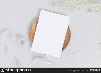 Greeting card or invitation card with white dry flower leaves on wood plate or tray in white background, top view  
