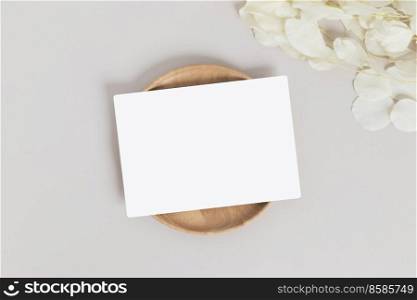 Greeting card or invitation card with white dry flower leaves on wood plate or tray in beige background