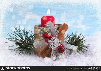 Greeting card with a candle and fir branches on a background with bokeh and snow