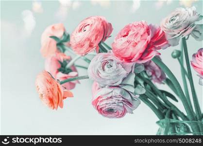 Greeting card with pastel color flowers and bokeh, floral border. Lovely Ranunculus flowers blooming at light blue background, floral border