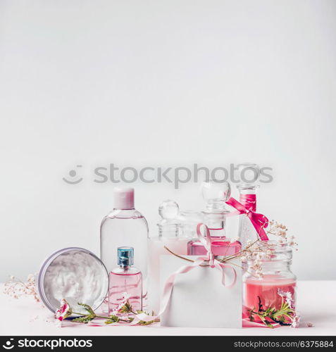 Greeting cosmetic set with perfume, skin care products and blank card with ribbon, front view, mock up