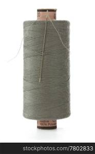 grey bobbin thread with a needle on white background
