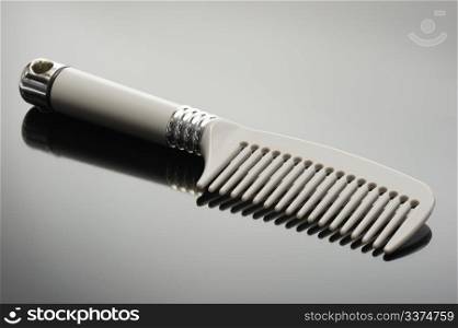 Grey comb and its reflection on a black background