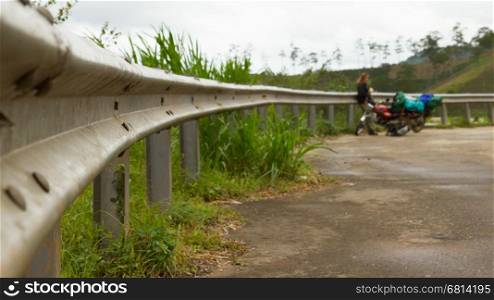 Grey guardrail on a rural roadside with a nice perspective, motorcycles and a woman