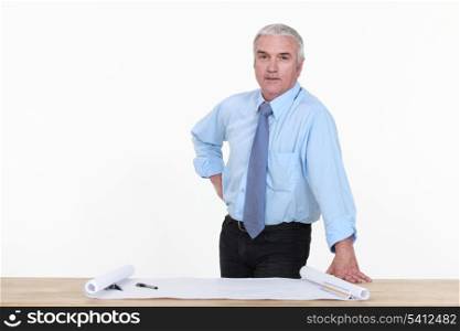 Grey-haired architect stood by work desk