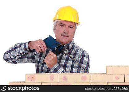 Grey-haired builder drilling into wall