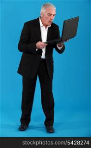 Grey-haired businessman holding portable computer