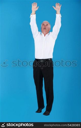 Grey haired businessman reaching into the air