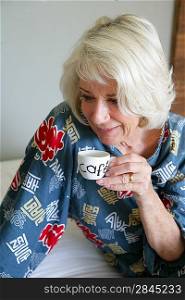 Grey-haired lady drinking her morning coffee