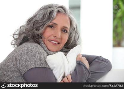Grey-haired lady holding cushion