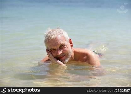 Grey-haired man laying in the sea