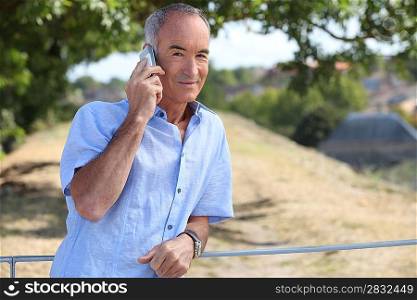 Grey-haired man making telephone call in park