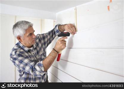 Grey-haired man replacing house paneling