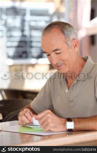 Grey-haired man sat in cafe drinking espresso