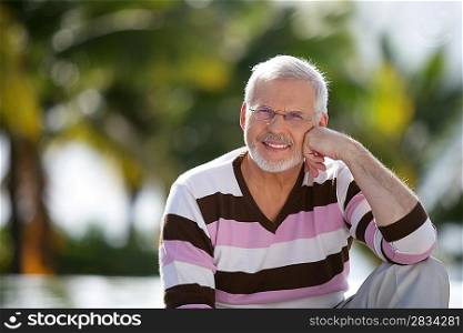 Grey-haired man sat in garden