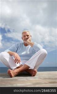 Grey haired man sat on jetty