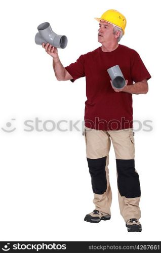 Grey-haired plumber holding two replacement parts