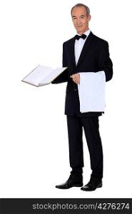 Grey haired waiter holding menu and table cloth