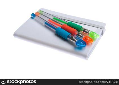 grey notebook diary or agenda and colored pens lying on the top (isolated on white background)