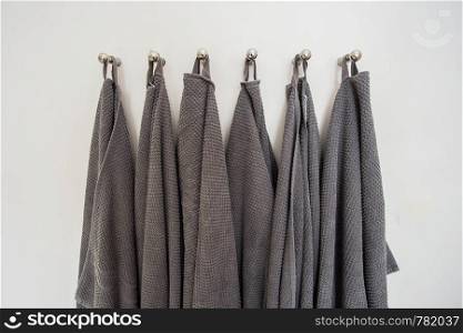 Grey towels hanging in a row, prepared on hanger. white wall close-up. Grey towels hanging in a row, prepared on hanger. white wall