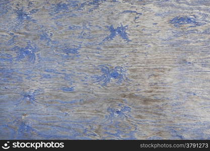 grey wooden board with knots and remnants of blue paint