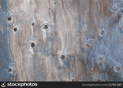 grey wooden board with knots and remnants of blue paint