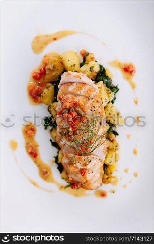 Grill chunk chicken breast baked potato and kale with lemon butter sauce red pepper and dill serving in white plate top view