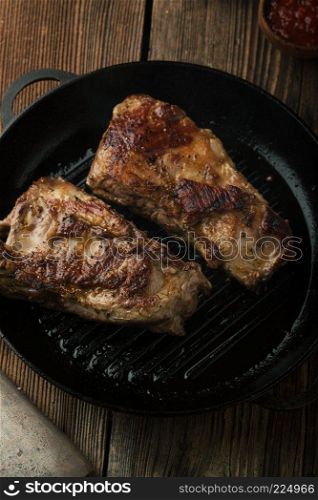 Grill Pork ribs with ketchup, mustard in a frying pan on a wooden table
