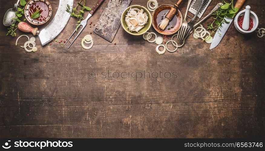 Grill seasoning and sauces with vintage kitchenware kitchen utensils Meat Fork and Butcher Cleaver , knife and herbs mezzaluna knife on wooden dark background, top view, border. BBQ and cooking