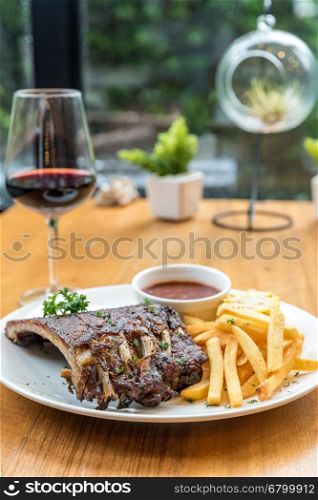 Grilled Barbecued Pork Baby Back Ribs grilled sweet corn and fries on dining table with red wine