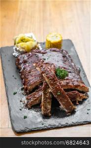 Grilled Barbecued Pork Baby Back Ribs with baked potato and grilled sweet corn