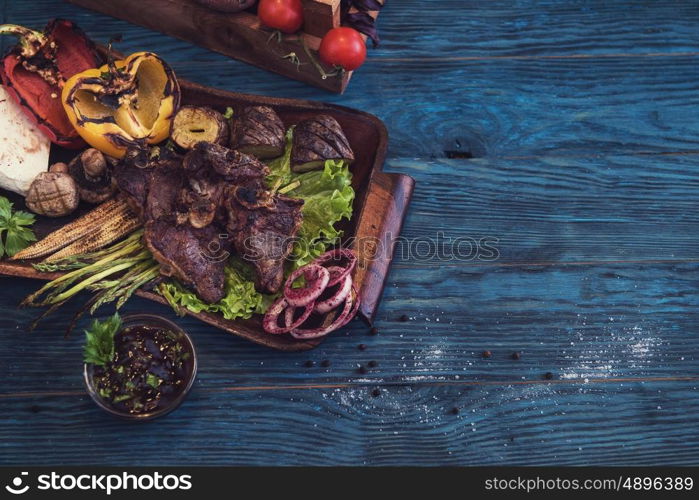 Grilled beef meat. Grilled beef meat with vegetable on a blue wooden background