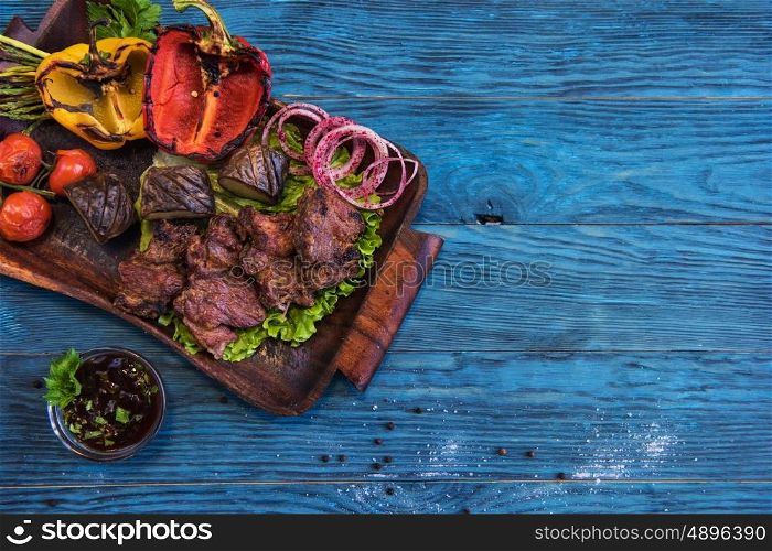 Grilled beef meat. Grilled beef meat with vegetable on a blue wooden background