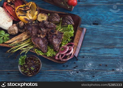 Grilled beef meat. Grilled beef meat with vegetable on a blue wooden background