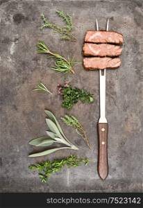Grilled beef meat with herbs and spices on metal kitchen desk. Food background