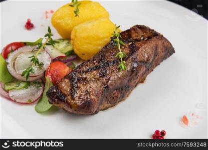 Grilled beef meat with potato and vegetables on white plate. Grilled beef meat