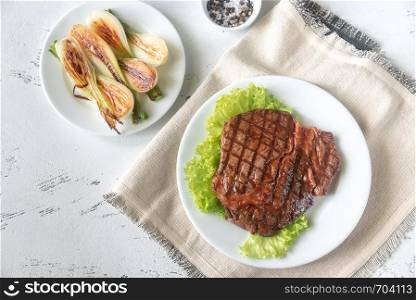 Grilled beef steak garnished with fresh lettuce and onions