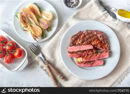 Grilled beef steak garnished with fresh lettuce, onions and cherry tomatoes
