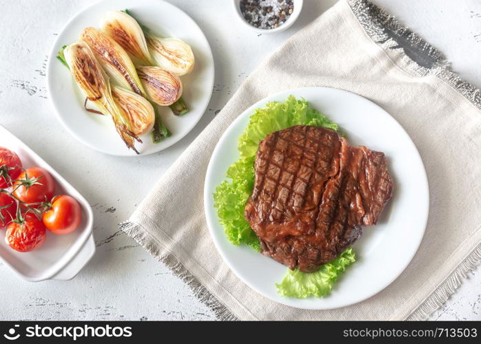 Grilled beef steak garnished with fresh lettuce, onions and cherry tomatoes