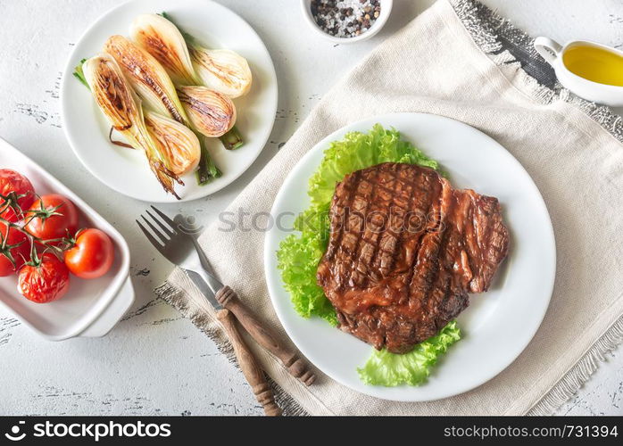 Grilled beef steak garnished with fresh lettuce, onions and cherry tomatoes