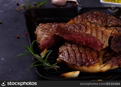 Grilled beef steak. Grilled beef steak in pan with spices on dark stone background
