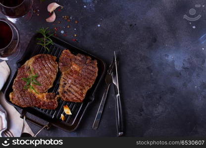 Grilled beef steak. Hot Grilled beef steak on dark background with two glasses of wine