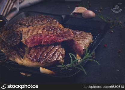 Grilled beef steak in pan with spices on dark background, retro toned. Grilled beef steak. Grilled beef steak