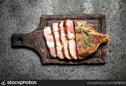 Grilled beef steak on a blackboard with spices. On rustic background.. Grilled beef steak on a blackboard with spices.