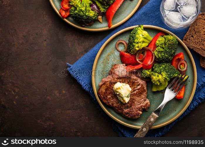 Grilled Beef steak with garlic butter and vegetables. Meat with grilled bell pepper, broccoli and onions. Top view.