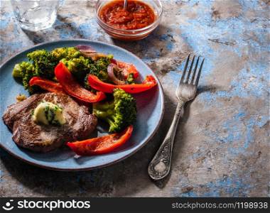 Grilled Beef steak with garlic butter and vegetables. Meat with grilled bell pepper, broccoli and onions.