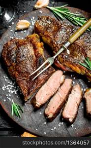 Grilled beef steak with rosemary and spices. On a black rustic background.. Grilled beef steak with rosemary and spices.